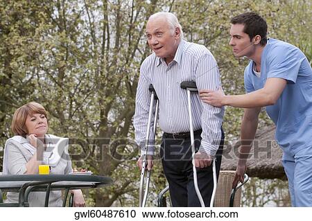 Stock Image - Health worker assisting a disabled man. Fotosearch