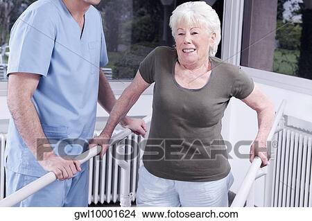 Picture - Health worker assisting a disabled woman in walking. Fotosearch