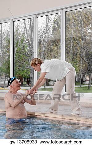Health worker assisting a man in coming out from a swimming pool View Large Photo Image Stock Image - Health worker assisting a man in coming out from a swimming pool. Fotosearch