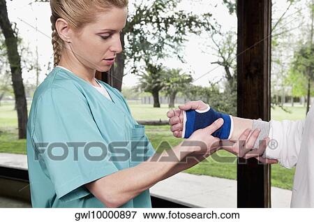 Health worker putting on a wrist brace to a disabled person View Large Photo Image Stock Photo - Health worker putting on a wrist brace to a disabled person. Fotosearch