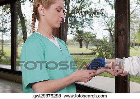 Health worker putting on a wrist brace to a disabled person View Large Photo Image Stock Photo - Health worker putting on a wrist brace to a disabled person. Fotosearch