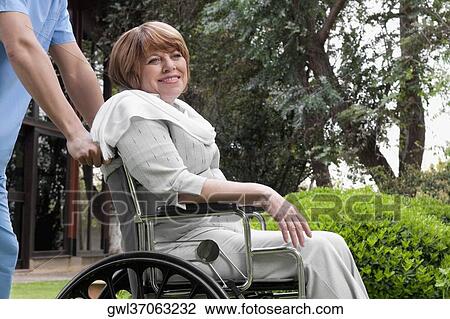 Healthcare worker pushing a woman sitting in a wheelchair View Large Photo Image Stock Image - Healthcare worker pushing a woman sitting in a wheelchair. Fotosearch