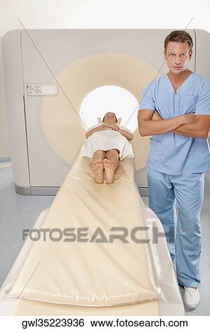 Stock Photograph - Healthcare worker standing beside a patient undergoing an MRI scan. Fotosearch