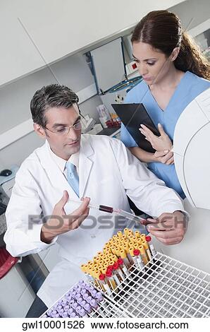 Stock Photograph - Lab technician filling blood in a test tube from a syringe. Fotosearch