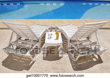 Lounge chairs with juices on table at the poolside View Large Photo Image Stock Image - Lounge chairs with juices on table at the poolside. Fotosearch