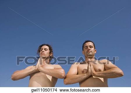 Low angle view of two men meditating View Large Photo Image Picture - Low angle view of two men meditating. Fotosearch