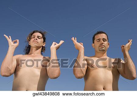 Low angle view of two men meditating View Large Photo Image Stock Photo - Low angle view of two men meditating. Fotosearch