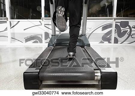 Picture - Low section view of a man running on a treadmill. Fotosearch