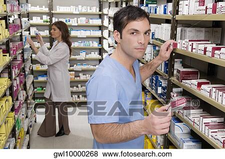 Stock Photo - Male and a female pharmacist checking the medicines in the medical store. Fotosearch