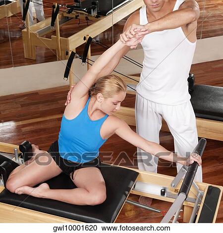 Male instructor assisting a woman in a gym View Large Photo Image Stock Image - Male instructor assisting a woman in a gym. Fotosearch