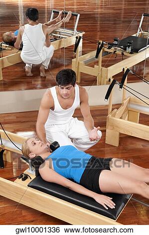 Male instructor assisting a woman in a gym View Large Photo Image Stock Photograph - Male instructor assisting a woman in a gym. Fotosearch