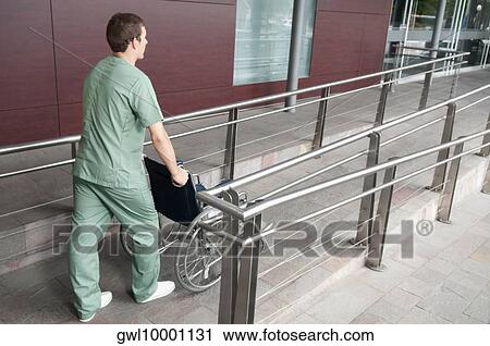 Male nurse carrying a wheelchair View Large Photo Image Stock Image - Male nurse carrying a wheelchair. Fotosearch