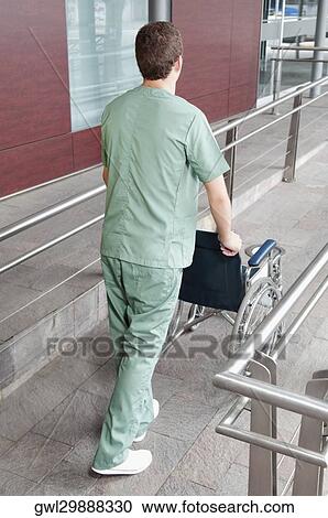 Male nurse carrying a wheelchair View Large Photo Image Stock Image - Male nurse carrying a wheelchair. Fotosearch
