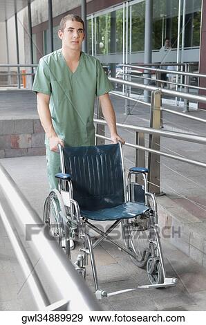 Male nurse carrying a wheelchair View Large Photo Image Stock Photo - Male nurse carrying a wheelchair. Fotosearch