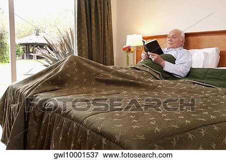 Male patient lying on the bed and reading a book View Large Photo Image Stock Photo - Male patient lying on the bed and reading a book. Fotosearch