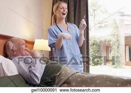 Male patient lying on the bed with a nurse standing beside him View Large Photo Image Stock Image - Male patient lying on the bed with a nurse standing beside him. Fotosearch