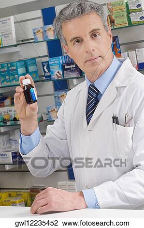 Male pharmacist holding a medicine bottle View Large Photo Image Stock Image - Male pharmacist holding a medicine bottle. Fotosearch