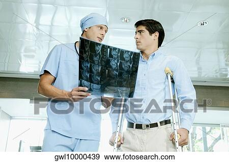 Male surgeon showing an X-Ray to a patient View Large Photo Image Stock Photo - Male surgeon showing an X-Ray to a patient. Fotosearch