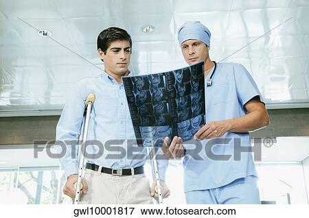 Stock Photo - Male surgeon showing an X-Ray to a patient. Fotosearch