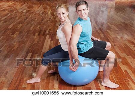 Man and a woman sitting back to back on a fitness ball View Large Photo Image Stock Photograph - Man and a woman sitting back to back on a fitness ball. Fotosearch