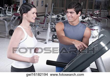 Picture - Man assisting a woman on a treadmill. Fotosearch