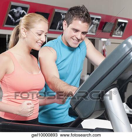Man assisting a woman on a treadmill View Large Photo Image Stock Image - Man assisting a woman on a treadmill. Fotosearch