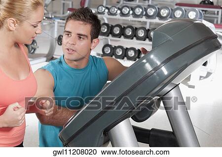 Man assisting a woman on a treadmill View Large Photo Image Stock Image - Man assisting a woman on a treadmill. Fotosearch