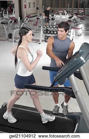 Man assisting a woman on a treadmill View Large Photo Image Stock Image - Man assisting a woman on a treadmill. Fotosearch