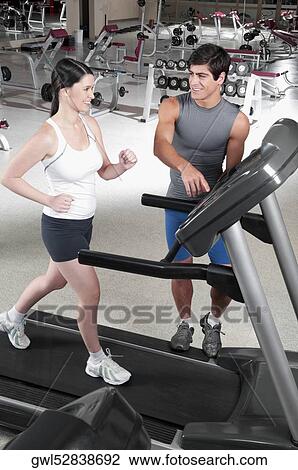 Man assisting a woman on a treadmill View Large Photo Image Stock Image - Man assisting a woman on a treadmill. Fotosearch