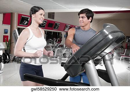 Man assisting a woman on a treadmill View Large Photo Image Stock Image - Man assisting a woman on a treadmill. Fotosearch
