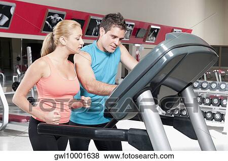 Man assisting a woman on a treadmill View Large Photo Image Stock Photo - Man assisting a woman on a treadmill. Fotosearch