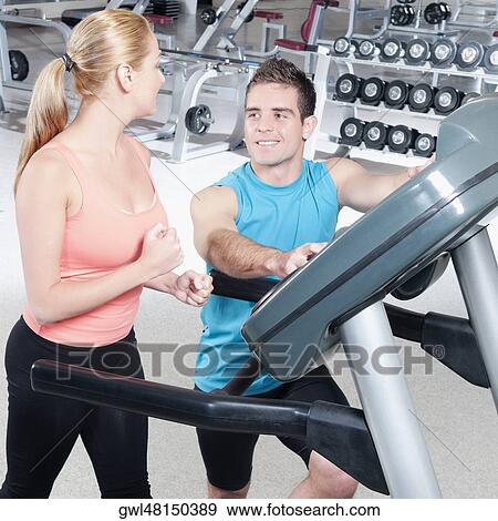 Man assisting a woman on a treadmill View Large Photo Image Stock Photo - Man assisting a woman on a treadmill. Fotosearch