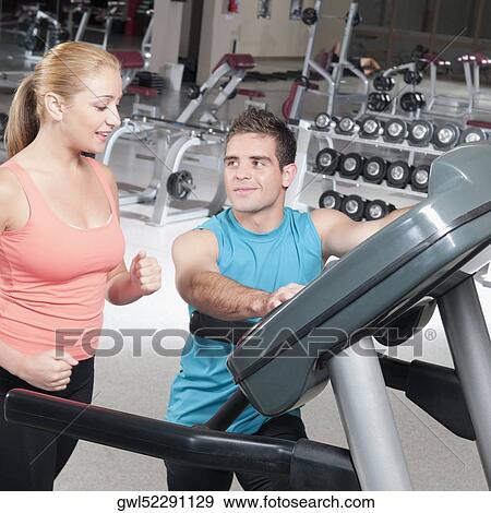 Stock Photo - Man assisting a woman on a treadmill. Fotosearch