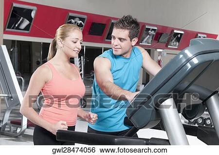 Man assisting a woman on a treadmill View Large Photo Image Stock Photograph - Man assisting a woman on a treadmill. Fotosearch