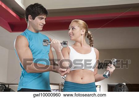 Man assisting a woman work out with dumbbells View Large Photo Image Stock Image - Man assisting a woman work out with dumbbells. Fotosearch
