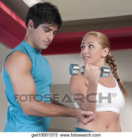 Man assisting a woman work out with dumbbells View Large Photo Image Stock Image - Man assisting a woman work out with dumbbells. Fotosearch