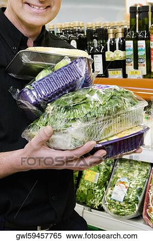 Stock Photography - Man buying vegetables in a supermarket. Fotosearch