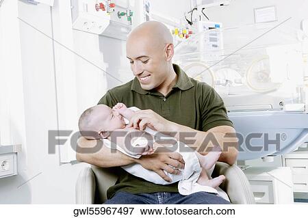 Man carrying his newborn baby View Large Photo Image Stock Photo - Man carrying his newborn baby. Fotosearch
