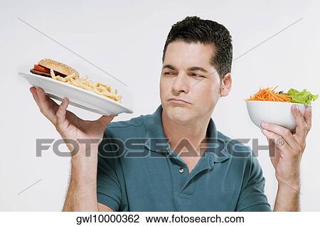 Man choosing between a hamburger plate and a salad bowl View Large Photo Image Stock Image - Man choosing between a hamburger plate and a salad bowl. Fotosearch
