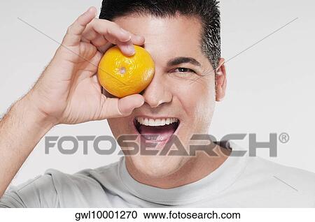 Man covering his eye with an orange View Large Photo Image Stock Image - Man covering his eye with an orange. Fotosearch