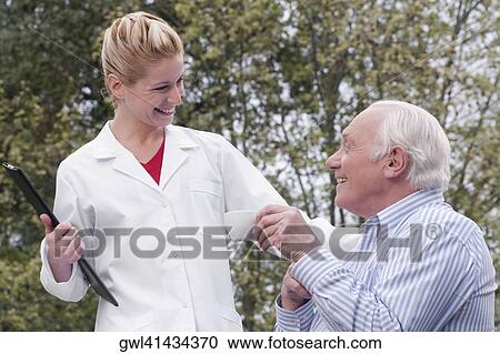 Man drinking tea with a doctor standing beside him View Large Photo Image Stock Image - Man drinking tea with a doctor standing beside him. Fotosearch