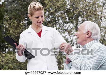 Man drinking tea with a doctor standing beside him View Large Photo Image Stock Photo - Man drinking tea with a doctor standing beside him. Fotosearch