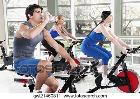 Man drinking water with two women working out in a gym View Large Photo Image Stock Image - Man drinking water with two women working out in a gym. Fotosearch