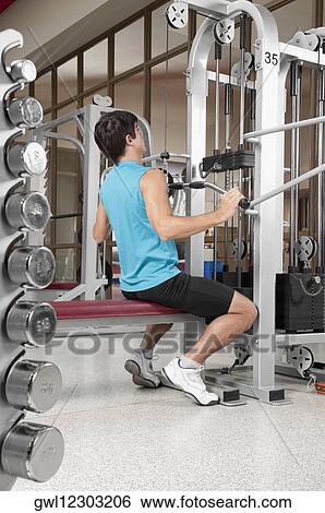 Man exercising in a gym View Large Photo Image Stock Photograph - Man exercising in a gym. Fotosearch