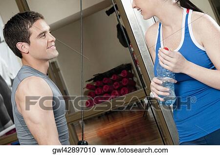 Man exercising in a gym with a woman smiling beside him View Large Photo Image Stock Image - Man exercising in a gym with a woman smiling beside him. Fotosearch