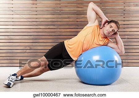 Stock Photo - Man exercising on a fitness ball in a gym. Fotosearch