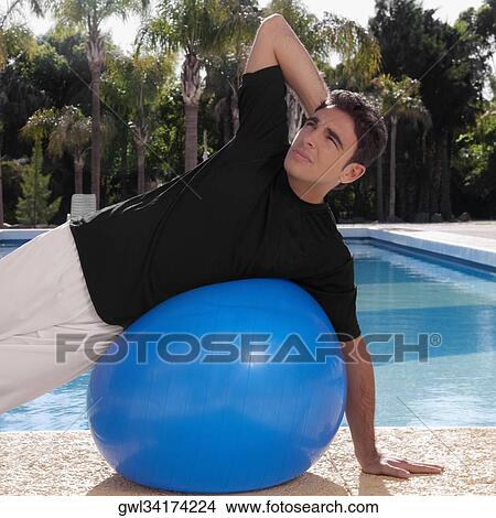 Man exercising with a fitness ball at the poolside View Large Photo Image Picture - Man exercising with a fitness ball at the poolside. Fotosearch