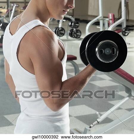 Man exercising with dumbbells in a gym View Large Photo Image Stock Image - Man exercising with dumbbells in a gym. Fotosearch