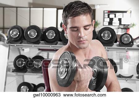 Man exercising with dumbbells in a gym View Large Photo Image Stock Image - Man exercising with dumbbells in a gym. Fotosearch