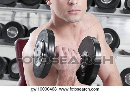 Man exercising with dumbbells in a gym View Large Photo Image Stock Photo - Man exercising with dumbbells in a gym. Fotosearch